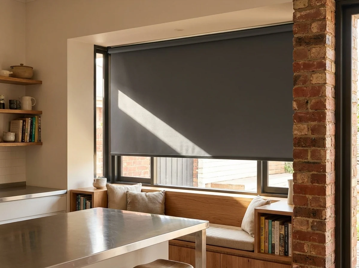 Charcoal blockout roller blind in a Brooklyn kitchen window seat nook, exposed brick pillar